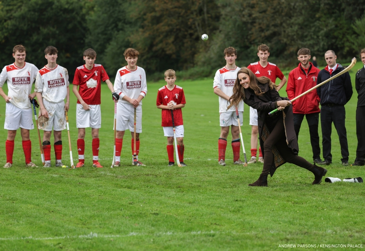 Kate Middleton playing shinty as members of Bute Shinty Club watch from the pitch