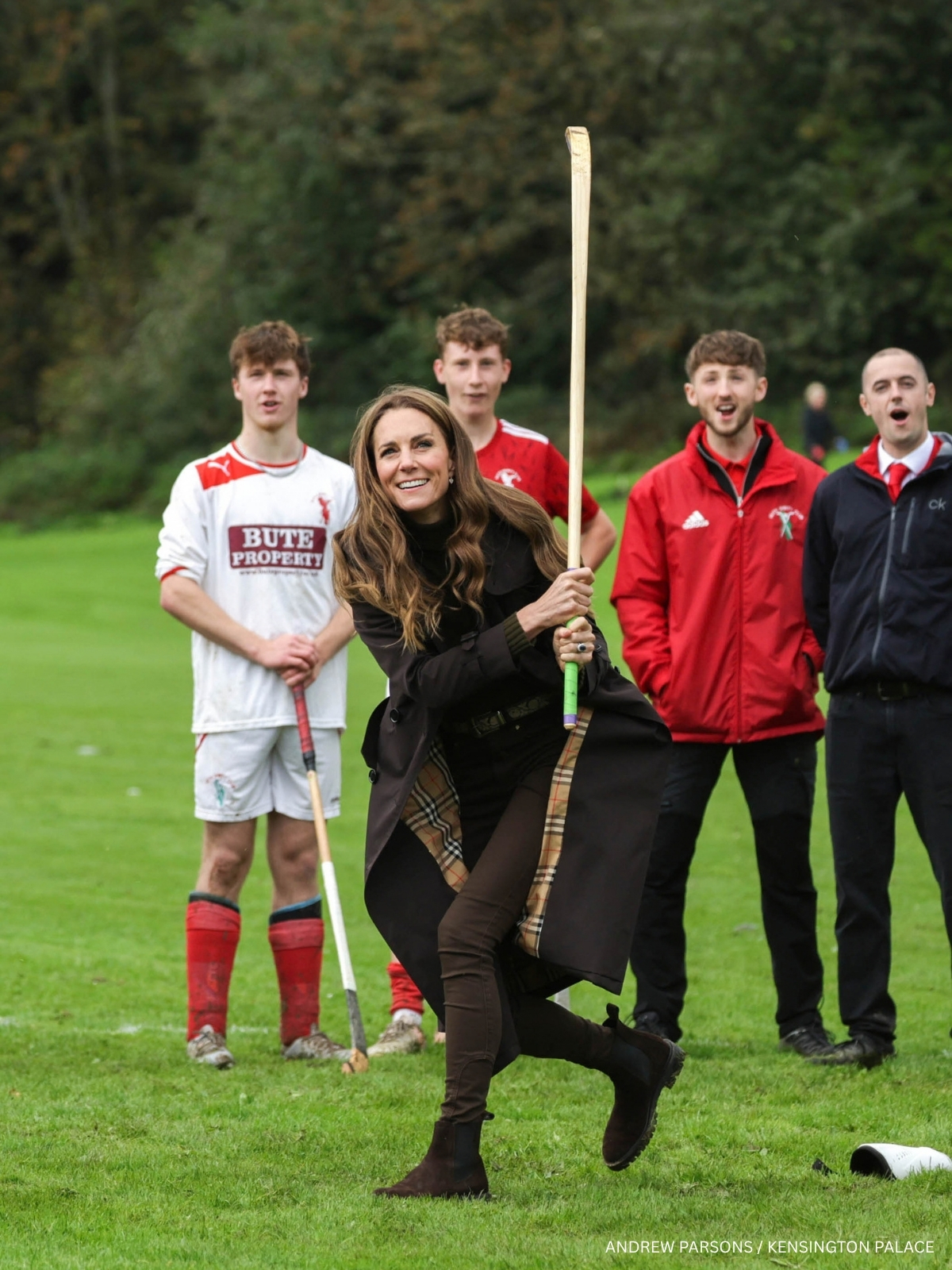 Kate Middleton playing shinty as members of Bute Shinty Club watch from the pitch