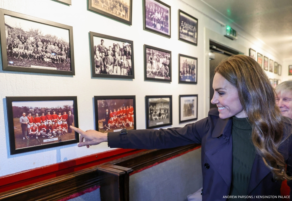 Kate Middleton pointing to a historic Bute Shinty Club team photograph inside the clubhouse
