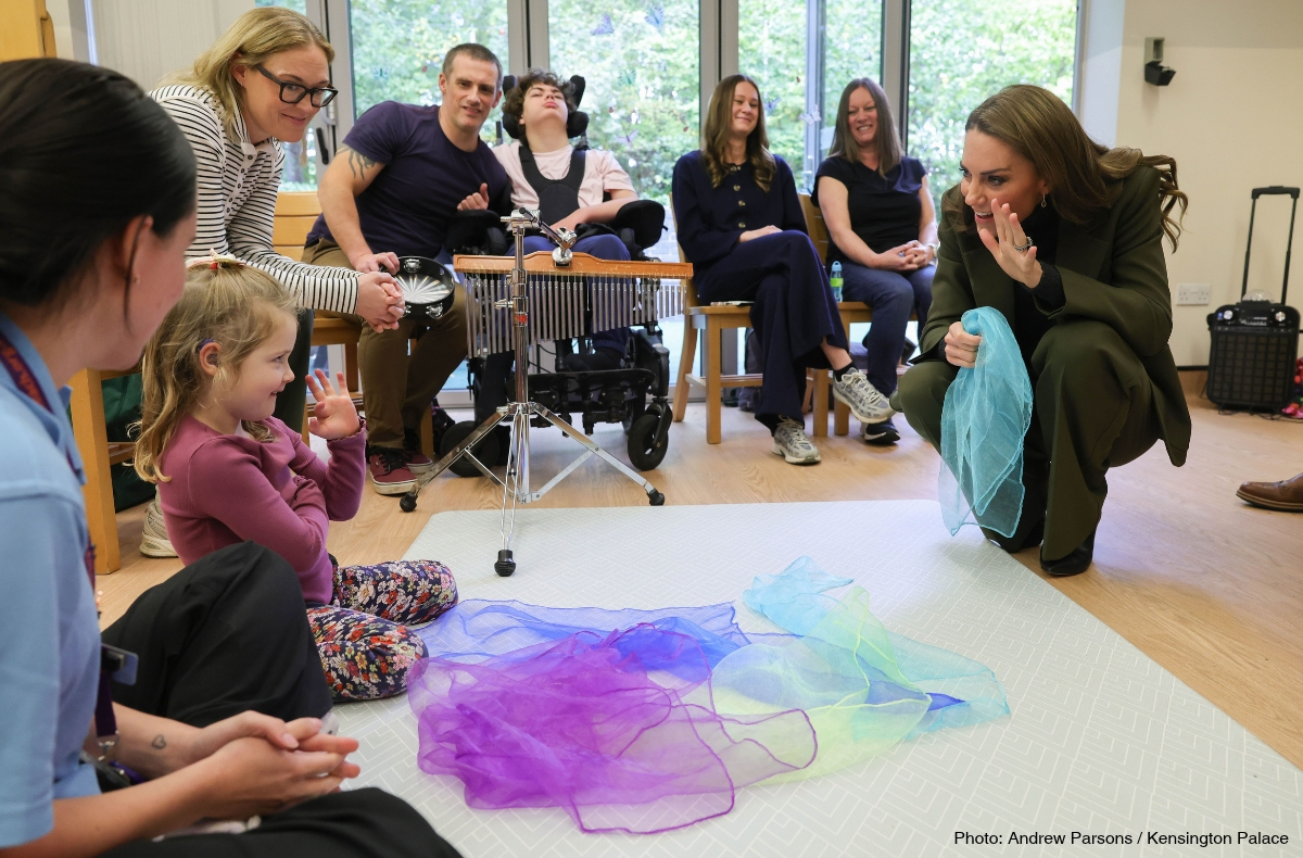 Kate Middleton crouching beside a young child during a group activity at The Treehouse