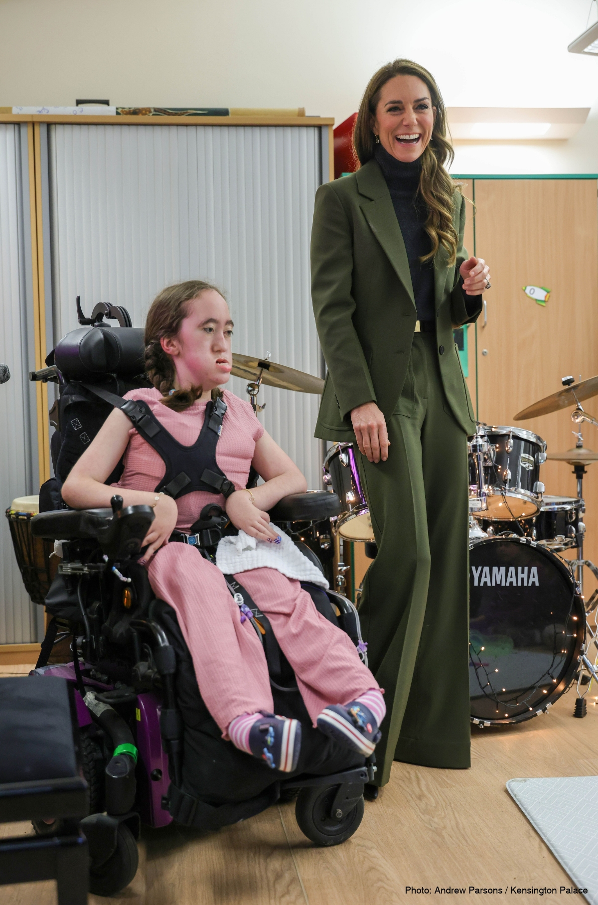 Kate Middleton standing beside a young wheelchair user in the music room at The Treehouse