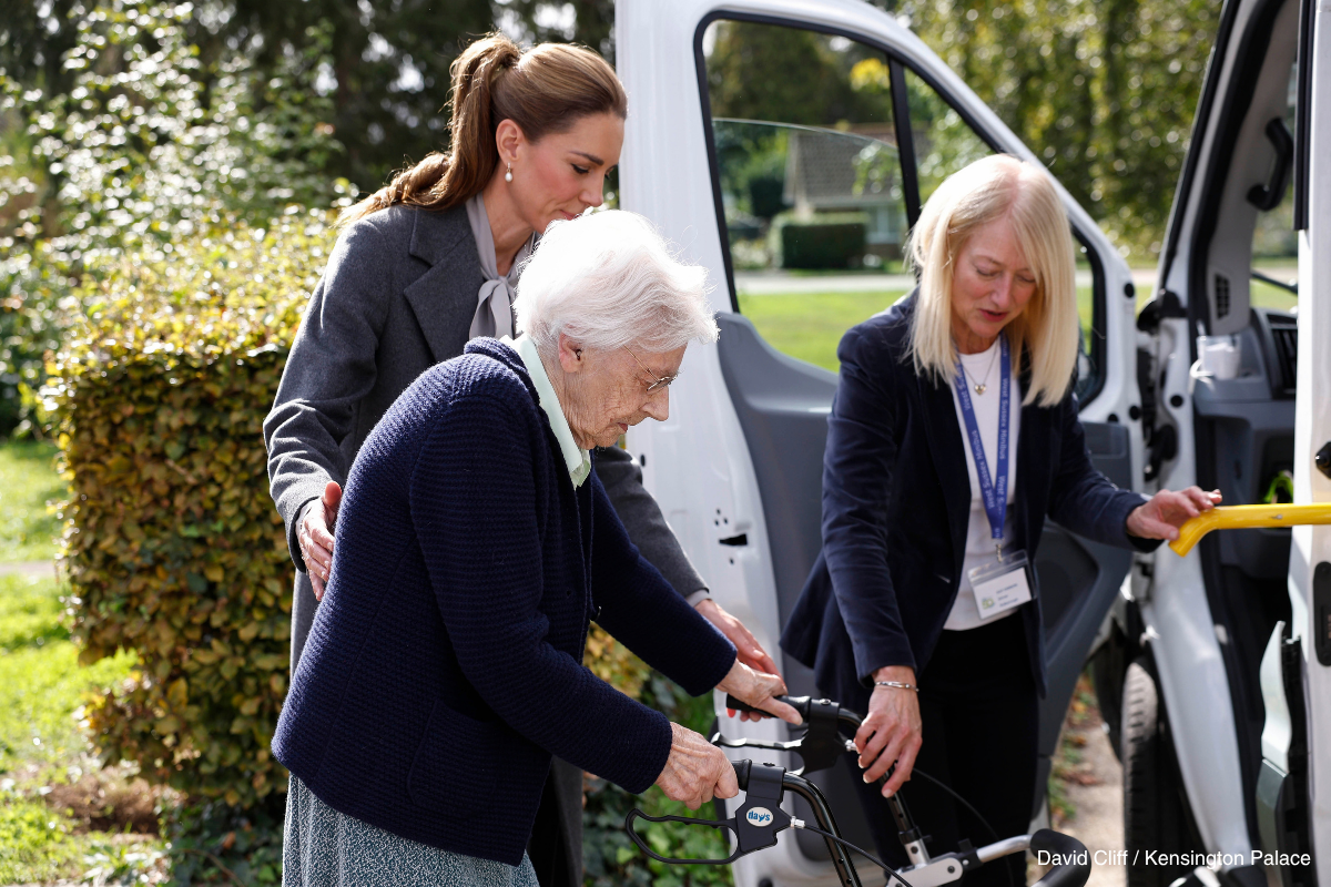 Kate Middleton standing beside a passenger and volunteer at the minibus door