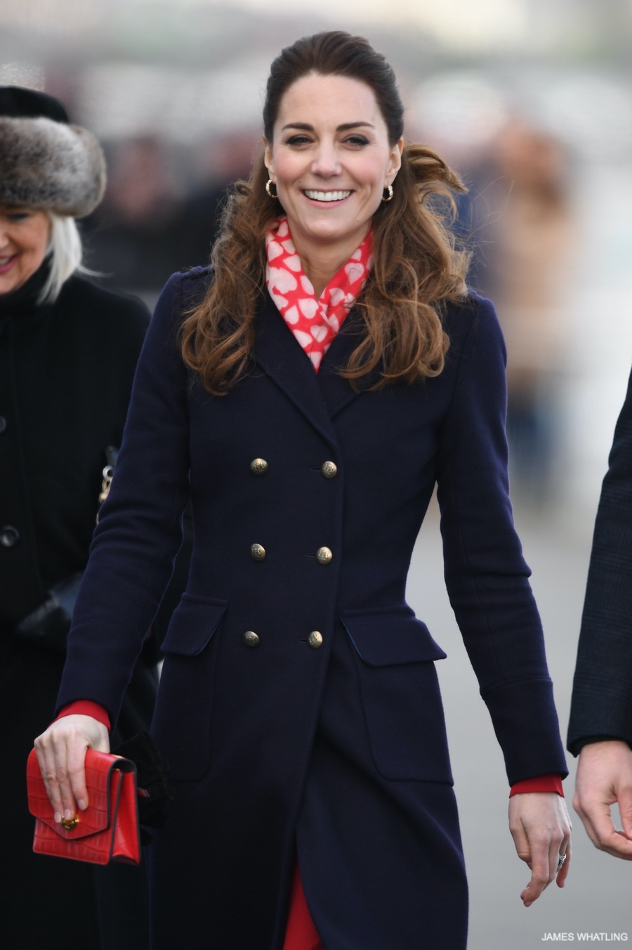 Kate Middleton wears a red heart print scarf over a blue winter coat.