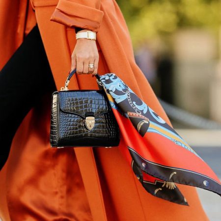 Model carrying the Aspinal of London Mayfair Midi Bag in Black with a scarf tied to to the handle.