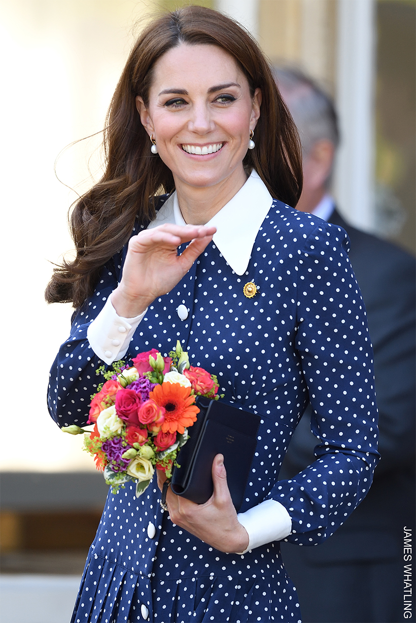 Kate Middleton in her blue polka dot dress, waving and holding flowers