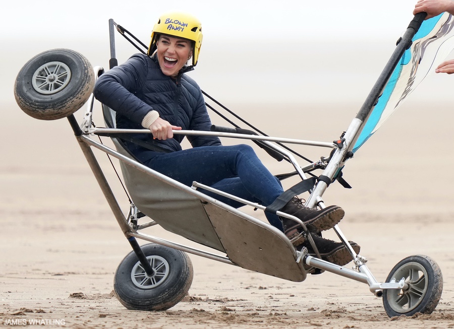 Kate Middleton participating in a 'land yachting' activity.  The sporty royal is wearing a yellow helmit and smiling.  She's wearing the blue puffer jacket described on this page, which is from Barbour.