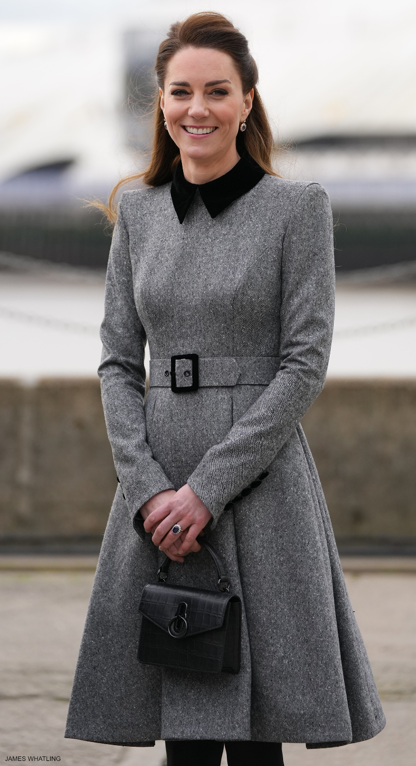 The Duchess of Cambridge (Kate Middleton) wearing a smart grey coat dress.  She carries a black croc-print bag with matching black hardware. 