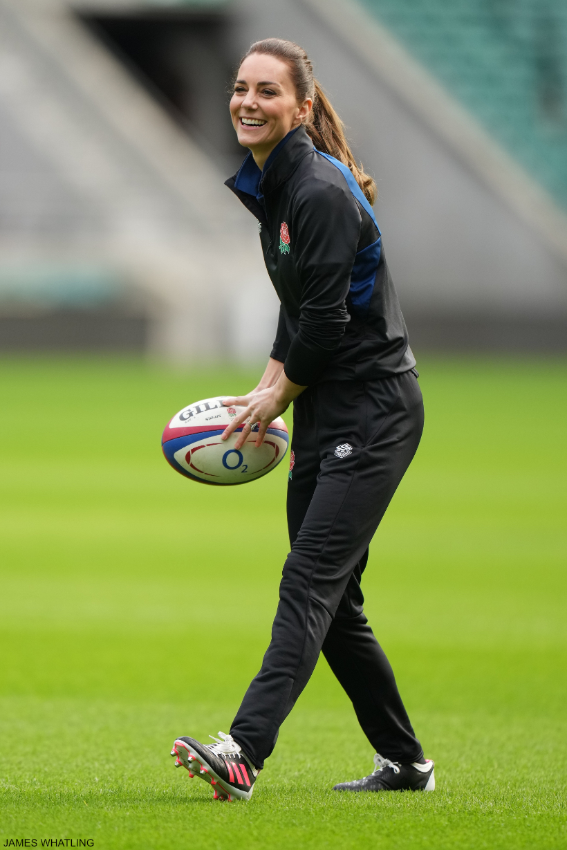 Sporty Kate wearing a rugby kit, and holding a rugby ball.