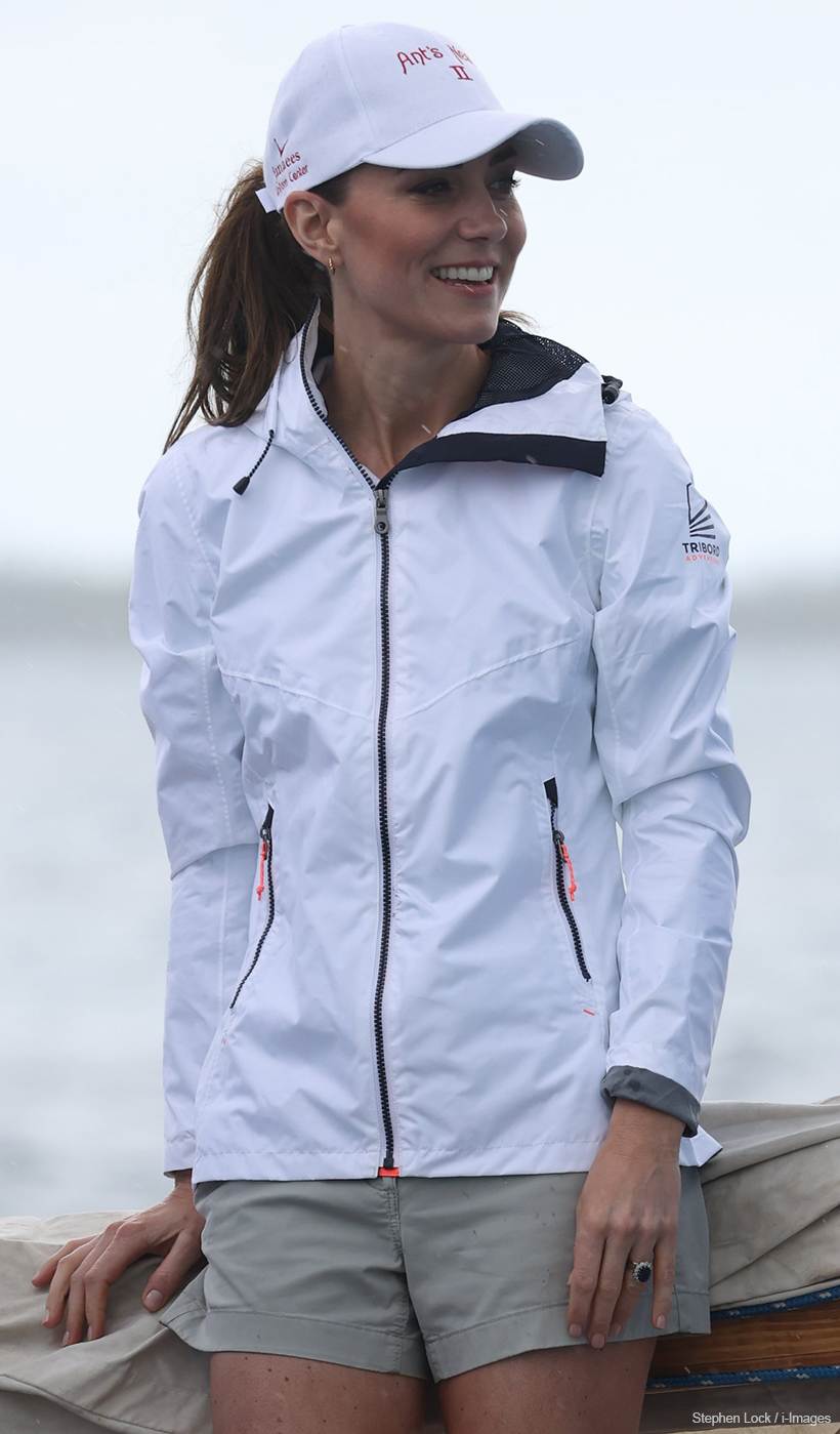 Kate Middleton wearing a white sailing jacket and hat onboard a sloop boat