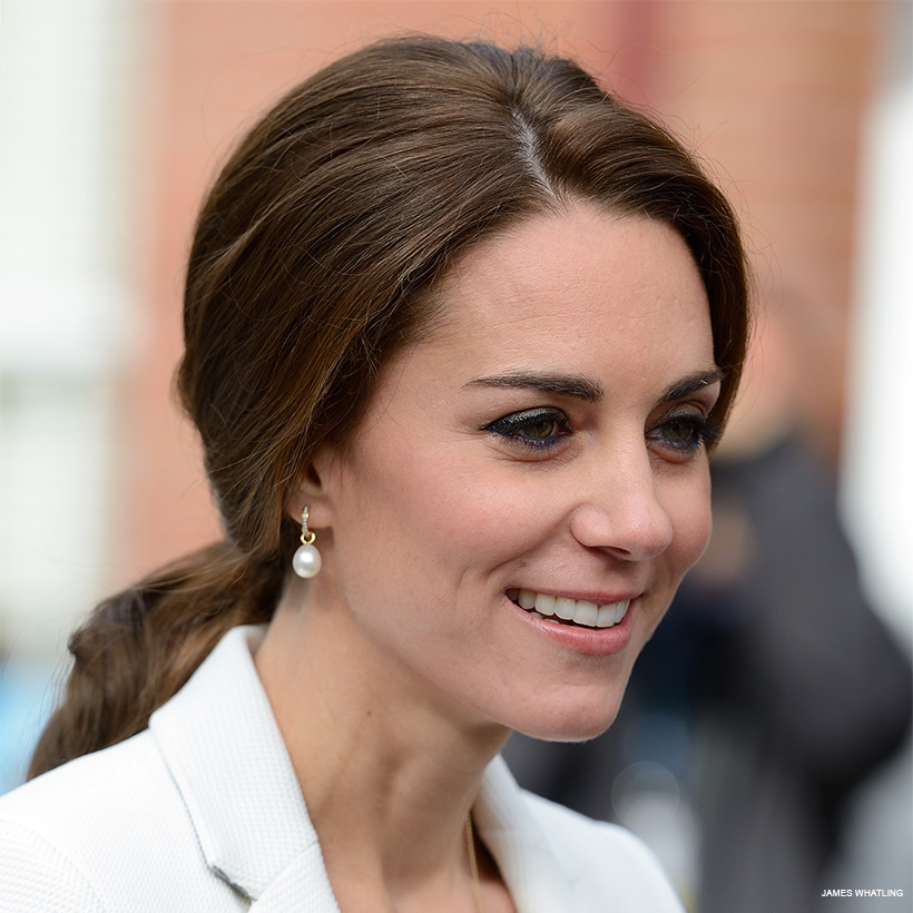 Kate Middleton wears her hair tied back, her pearl earrings are clearly on display.