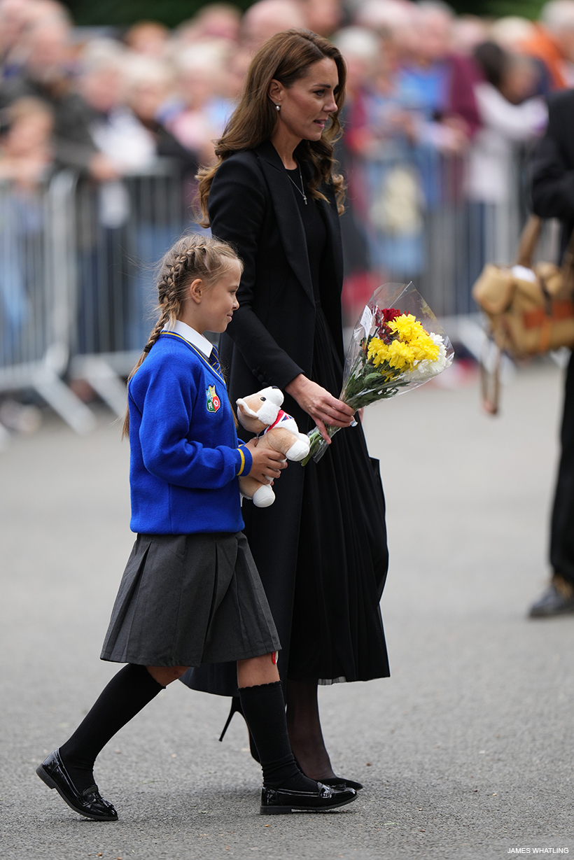 Kate accompanies a schoolgirl to leave a bunch of flowers and a stuffed corgi toy at the gates in Sandringham
