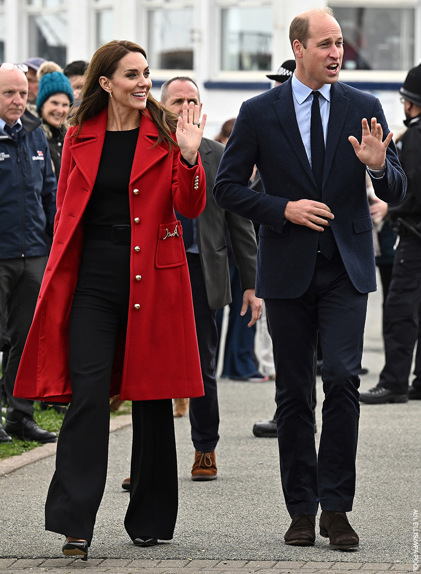 Prince William and Kate Midldeton visiting Wales.  The pair are waving to crowds waiting.  The Princess is wearing a bold red coat.