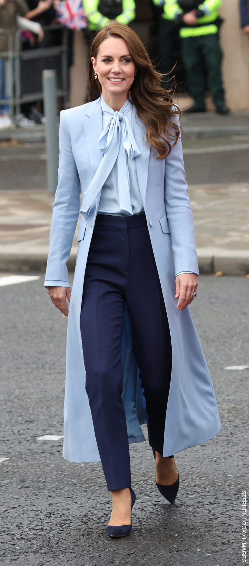 Kate Middleton, the Princess of Wales, dressed head-to-toe in blue.  The Princess is wearing the Winser Bow Blouse tied in a knot at the neckline. 