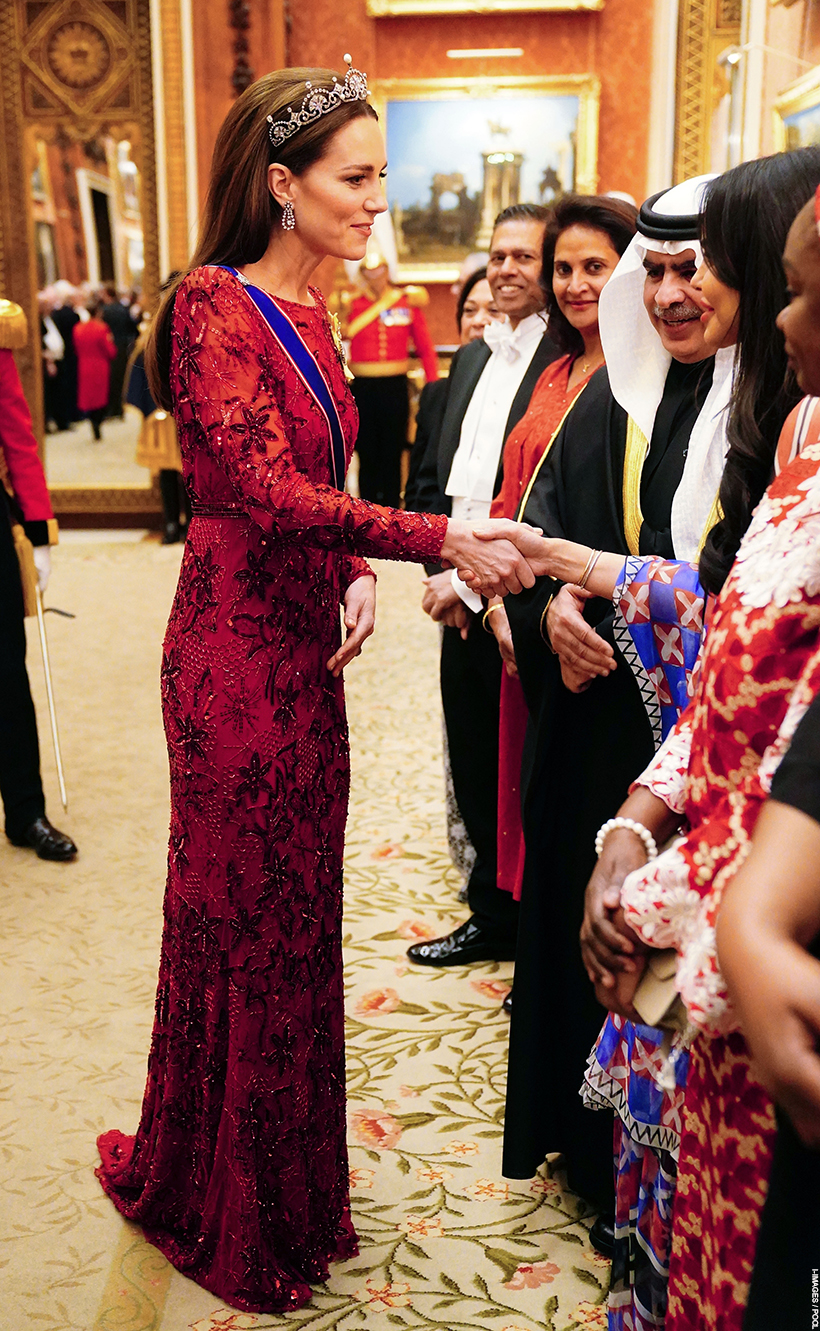 The Princess of Wales at the 2022 Diplomatic Reception.  Kate wears a red glittering gown, the Lotus Flower Tiara plus a pair of chandelier earrings. She is shaking hands with guests.