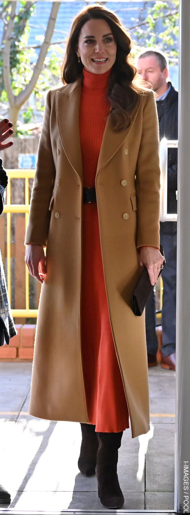 Kate Middleton wears a camel coat over orange-red separates while visiting a nursery school in Luton