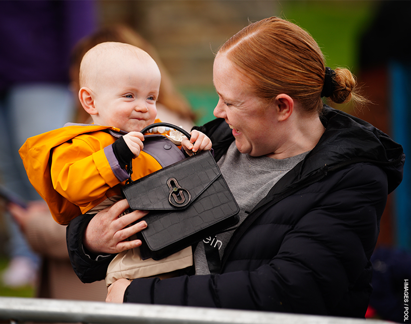 a baby plays with Kate Middleton's handbag
