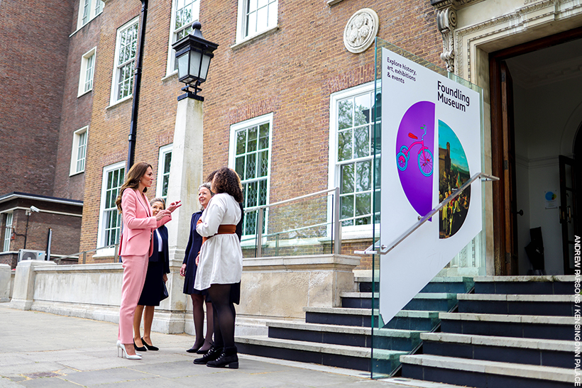 Kate Middleton enters the Foundling Museum.  She's wearing a pink suit with pearl accessories. 