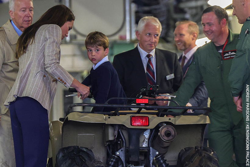 Prince Louis inside a quad bike, his mother helps him