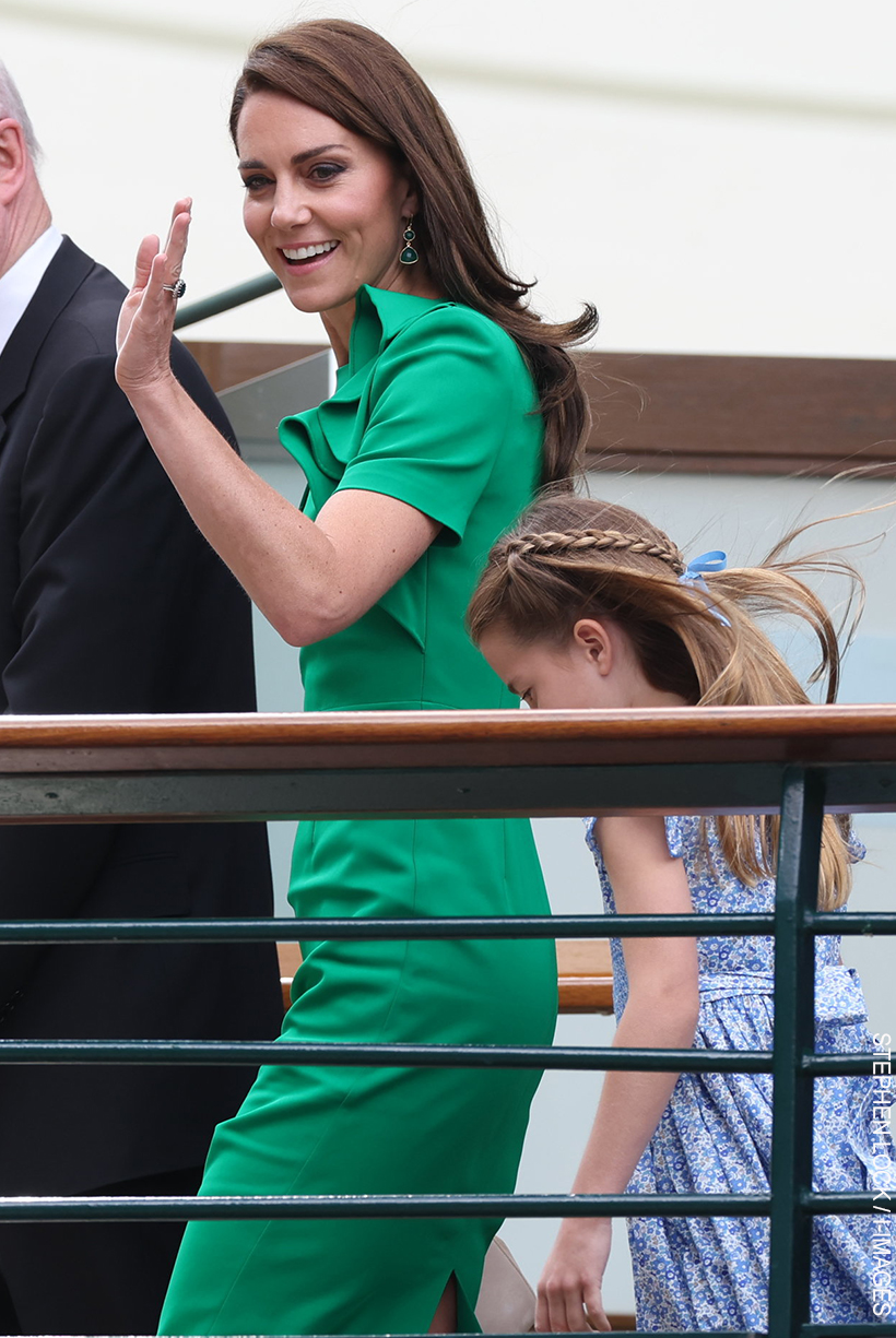 Kate Middleton wears green dress and matching green/gold earrings at Wimbledon. Princess waves to onlookers as she walks over a bridge with her Daughter, Princess Charlotte.