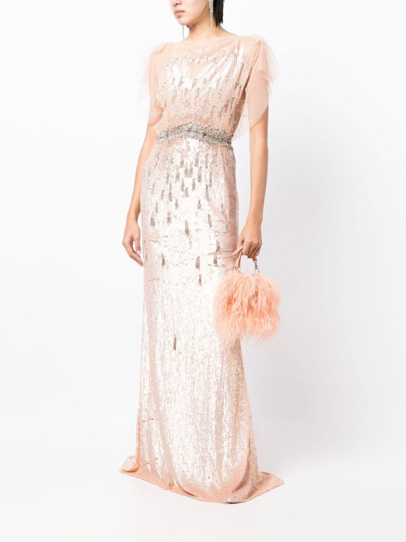 A shot of a model wearing the pink sequinned dress, while holding a fluffy pink handbag.  The model stands in front of a white background.