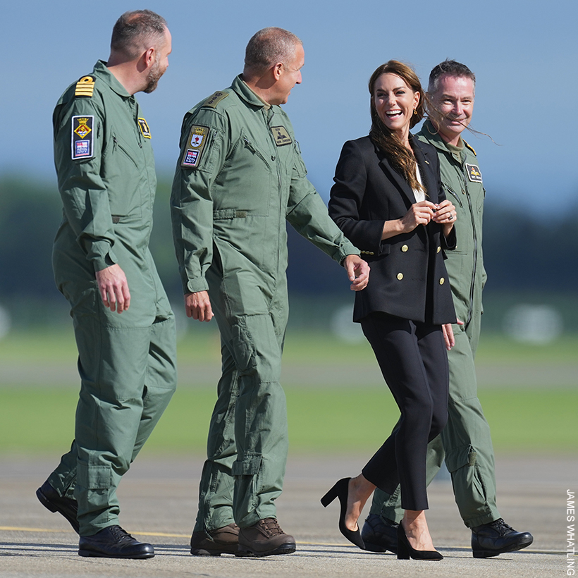 Kate Middleton, dressed in black, chatting and laughing with naval officers.