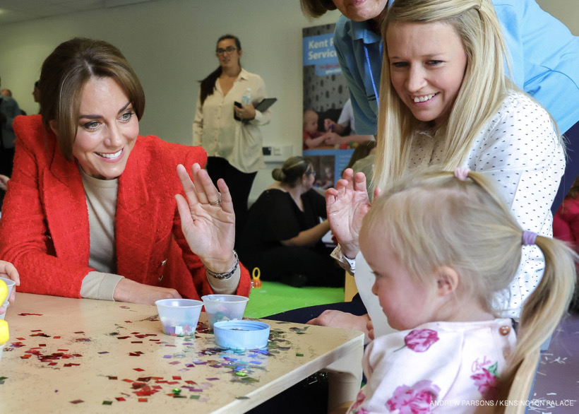 The Princess of Wales gets involved with messy play at a family portage session in Kent.  Kate waves at a little girl who is playing with glitter.