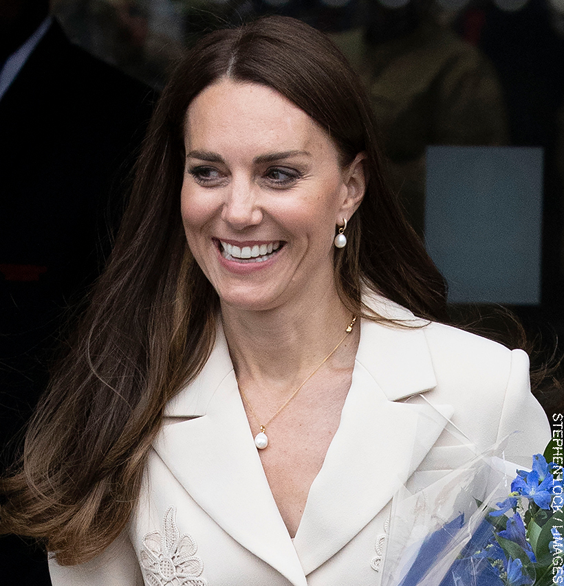 Kate Middleton, dressed in cream, wearing pearl drop earrings and a pearl necklace. 