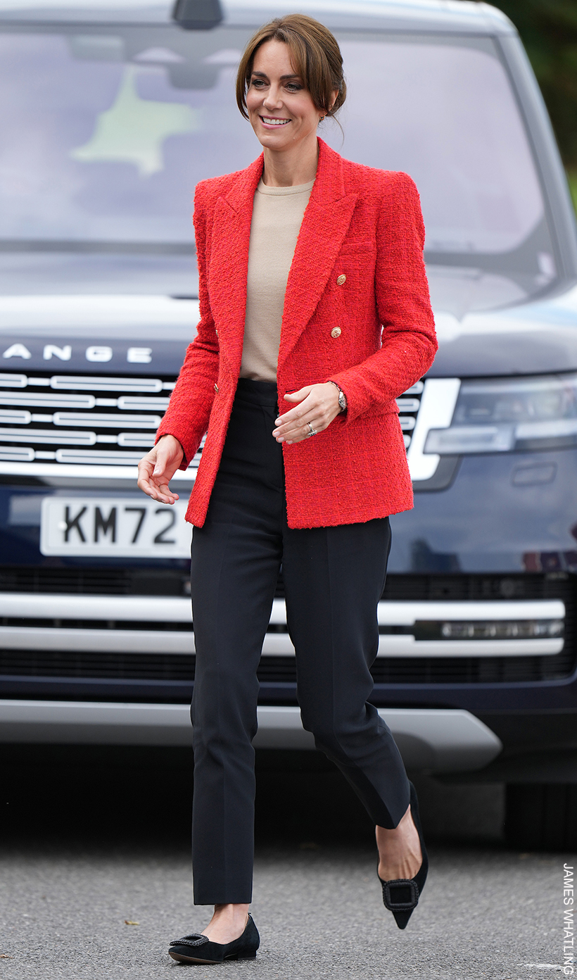 Kate Middleton walks towards the children's centre wearing a red blazer from Zara and black pointed flat shoes from Boden.
