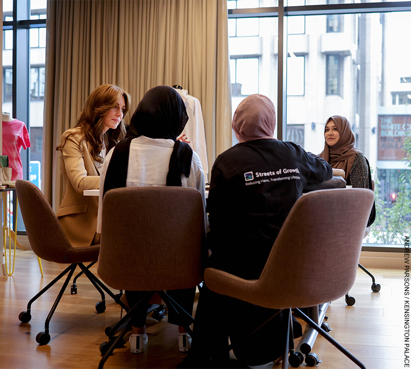 The Princess sits with women from Streets of Growth.  They are sat in conversation. 