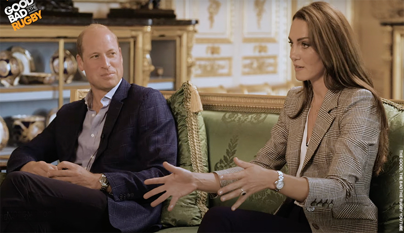 William and Kate talking to the podcast hosts.  Kate, dressed in her check blazer, is talking with her hands open.  William is looking at her, smiling. 