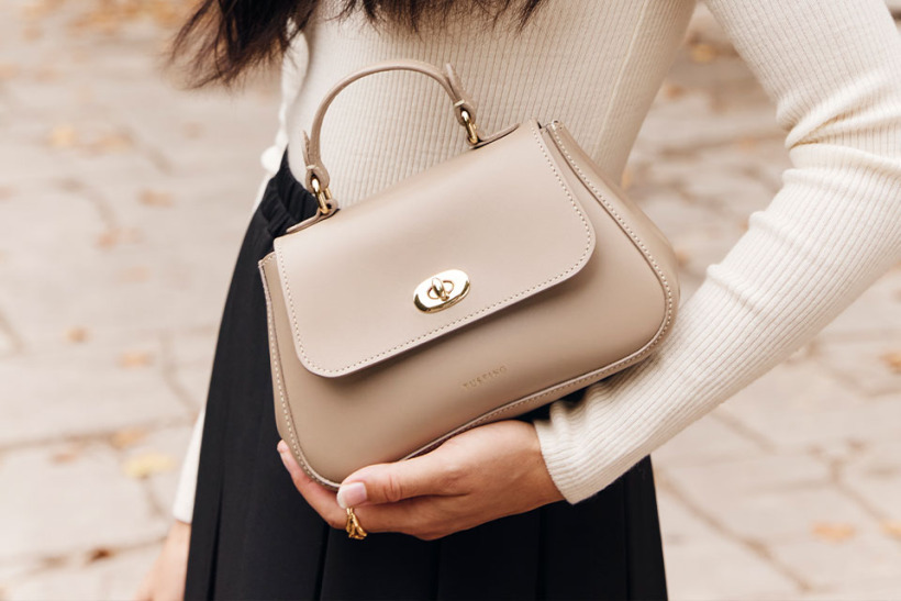 Model holding the Mini Holly bag by Tusting in taupe.