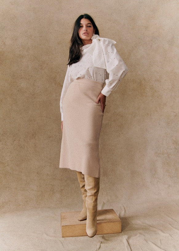 Product image from Sézane showing the model wearing the cream knit skirt.  A white Broderie Anglaise blouse is tucked in the top of the skirt.