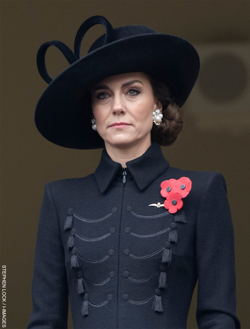 A profile shot of Kate Middleton wearing a sombre, military-inspired coat and a wide-brimmed hat, both in black, complemented by a delicate pearl and diamond earring and a red poppy brooch on her lapel.