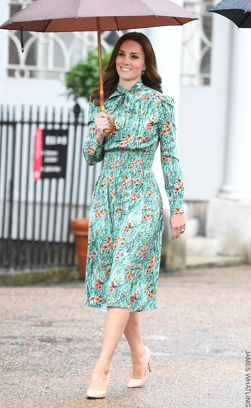 The Princess of Wales smiles as she braves the rain, holding an umbrella, wearing a green poppy print dress and nude heels