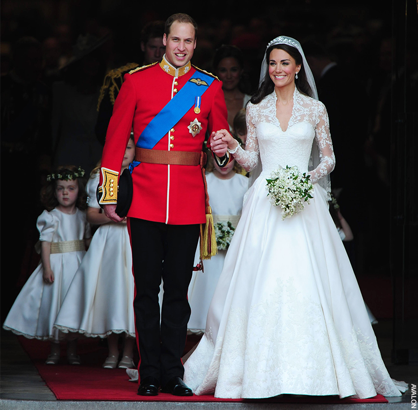 William and Kate on their wedding day. William wears full ceremonial uniform.  Kate is a vision in lace - a plunging neckline that stops at a sweetheart bodice, lace sleeves and a soft pleated lace skirt. 