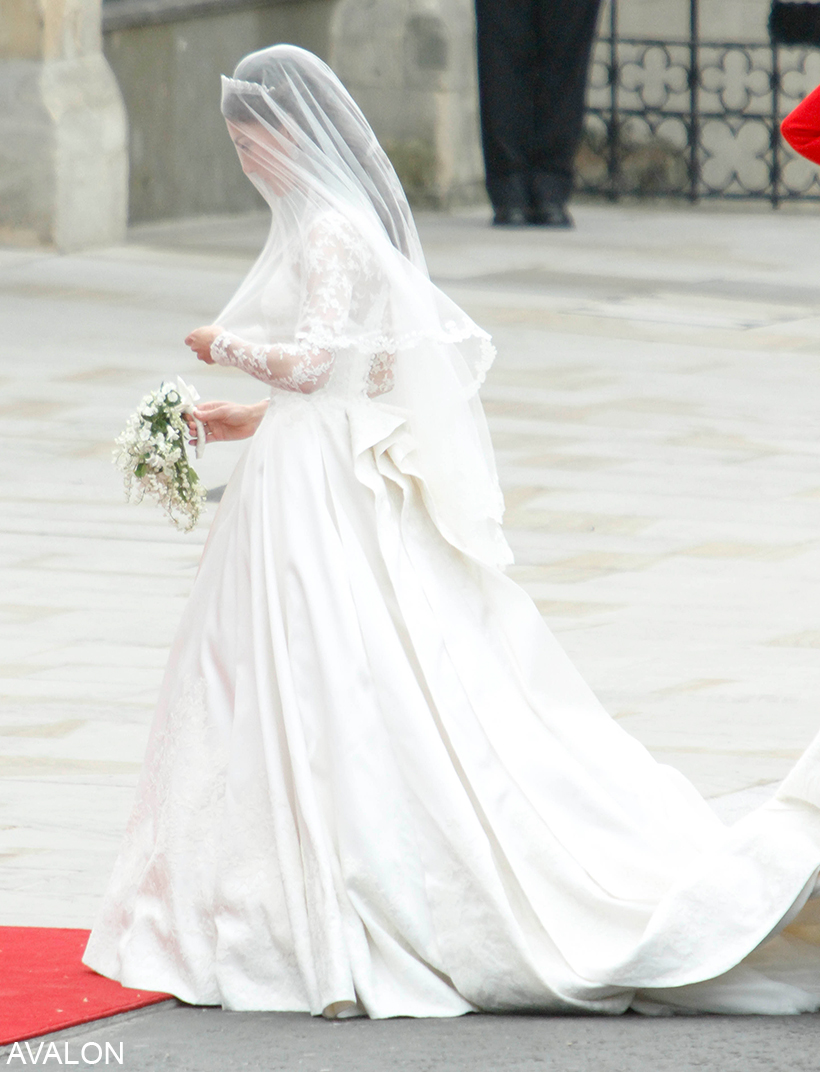 Kate Middleton stops for a second to adjust her veil before she steps into Westminster Abbey. The sideways photo shows her voluminous bridal gown.