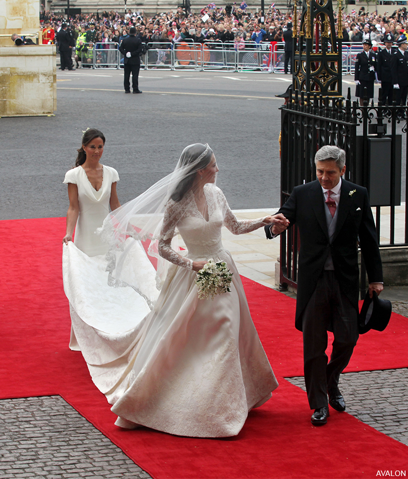Clad in her white wedding dress, Kate Middleton takes her father's hand as she steps into Westminster Abbey.  Sister Pippa holds the bride's train.