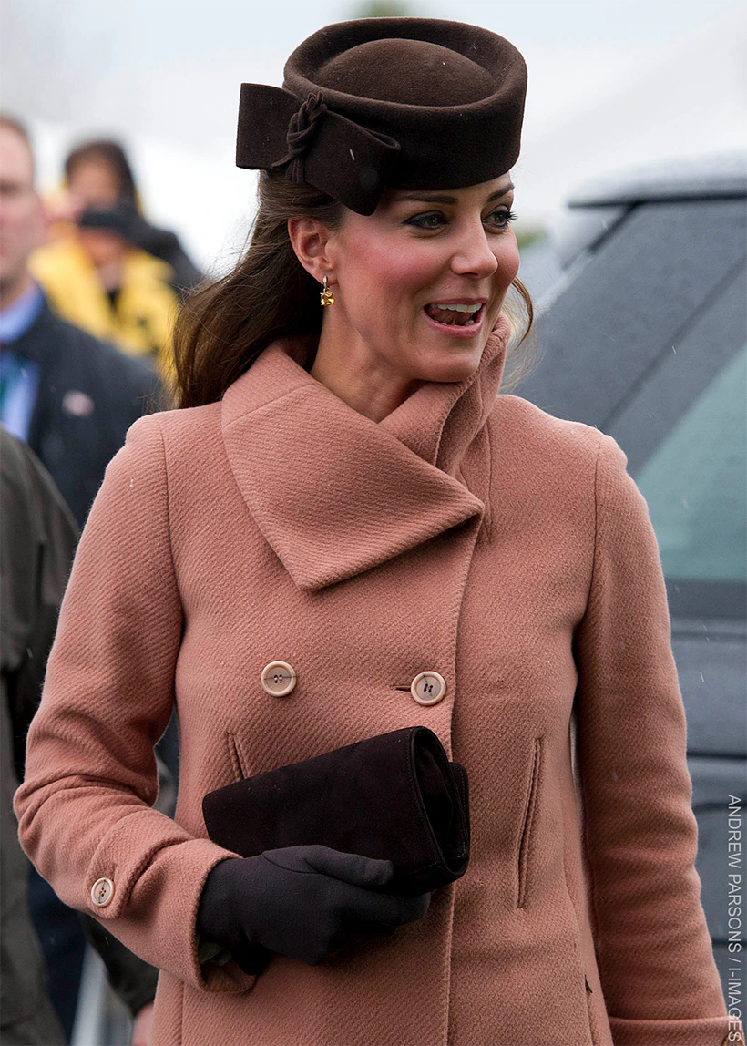 9 times Kate Middleton altered & upcycled her outfits 19 Kate Middleton wearing a salmon-coloured Joseph coat with a wide collar and double-breasted buttons, paired with a brown hat and black gloves, holding a black clutch, during her appearance at the Cheltenham Festival in 2013.