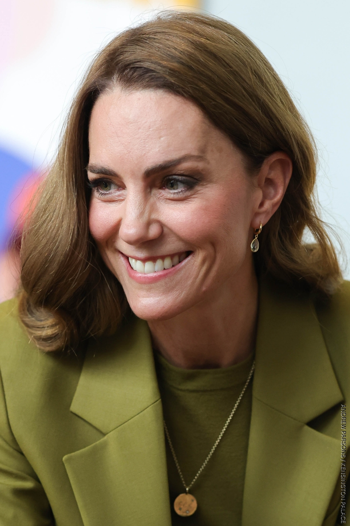 A close-up of the Princess of Wales smiling. She is wearing a pair of green amethyst pear drop earrings