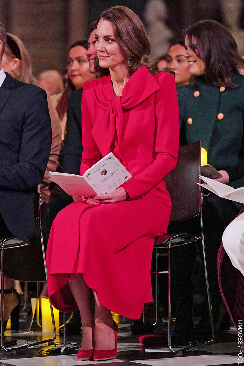 Kate Middleton, seated, reading a programme, wearing a red coat with a bow at the 2021 'Together At Christmas' Carol Service.