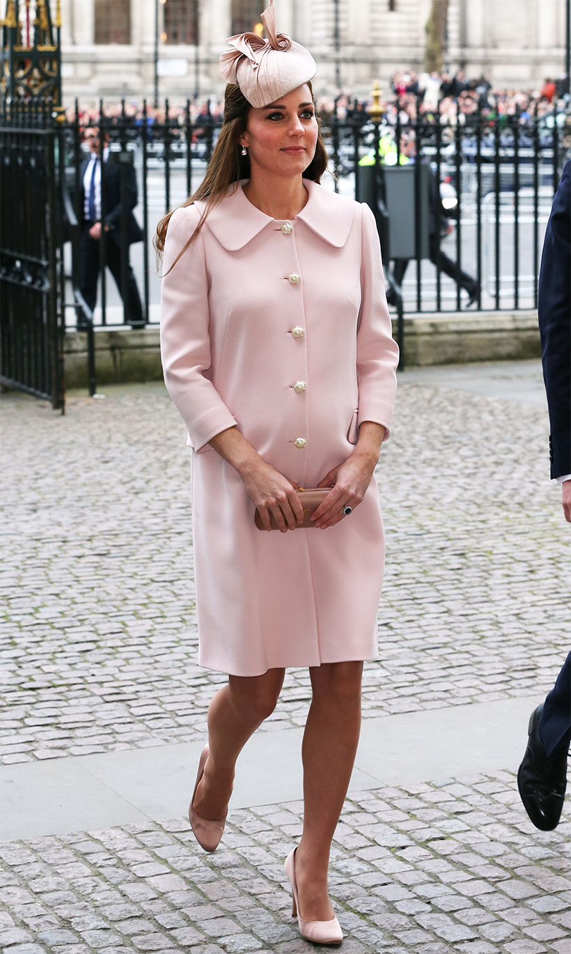 Catherine, Princess of Wales (then the Duchess of Cambridge), arrives at a formal event wearing a pastel pink coat dress with pearl buttons, a matching blush-colored hat with ribbon detailing, nude heels, and a coordinating clutch bag. 