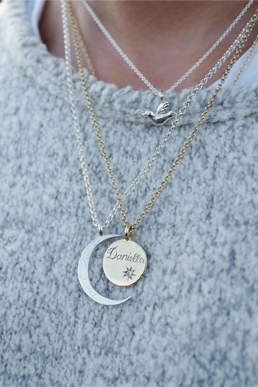 Model wearing a selection of Daniella Draper necklaces, includng the midnight moon style
