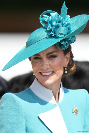 The Princess of Wales - Kate Middleton - smiling wearing formal attire and a hat in the colour teal