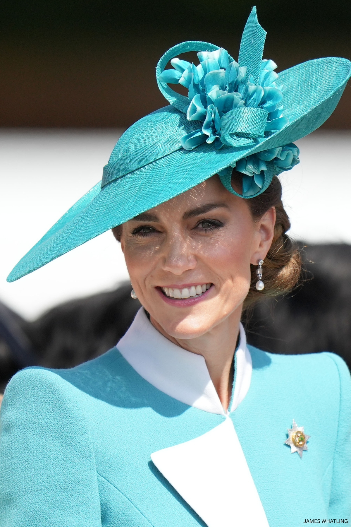 The Princess of Wales - Kate Middleton - smiling wearing formal attire and a hat in the colour teal
