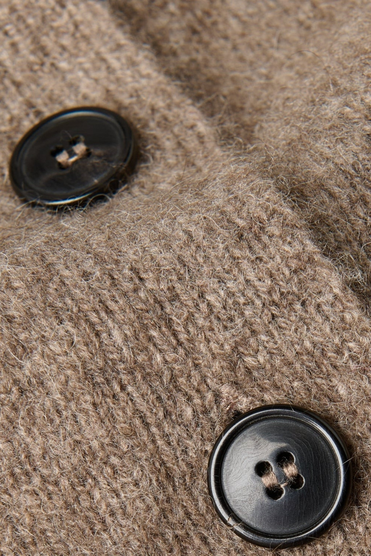 An extremely close-up shot of the brown cardigan, showing its wool fibres and the buttons