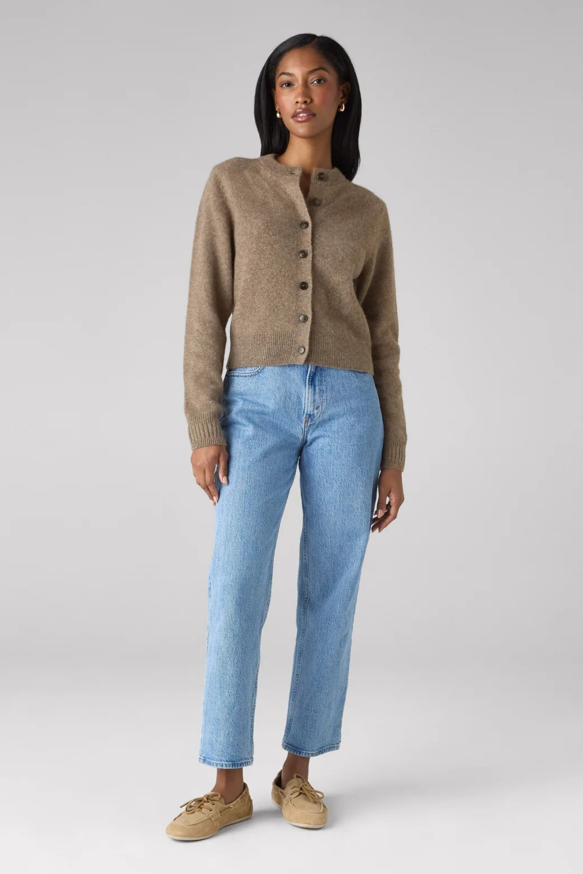 The model wears the brown cardigan with light blue cropped jeans and a pair of deck shoes.