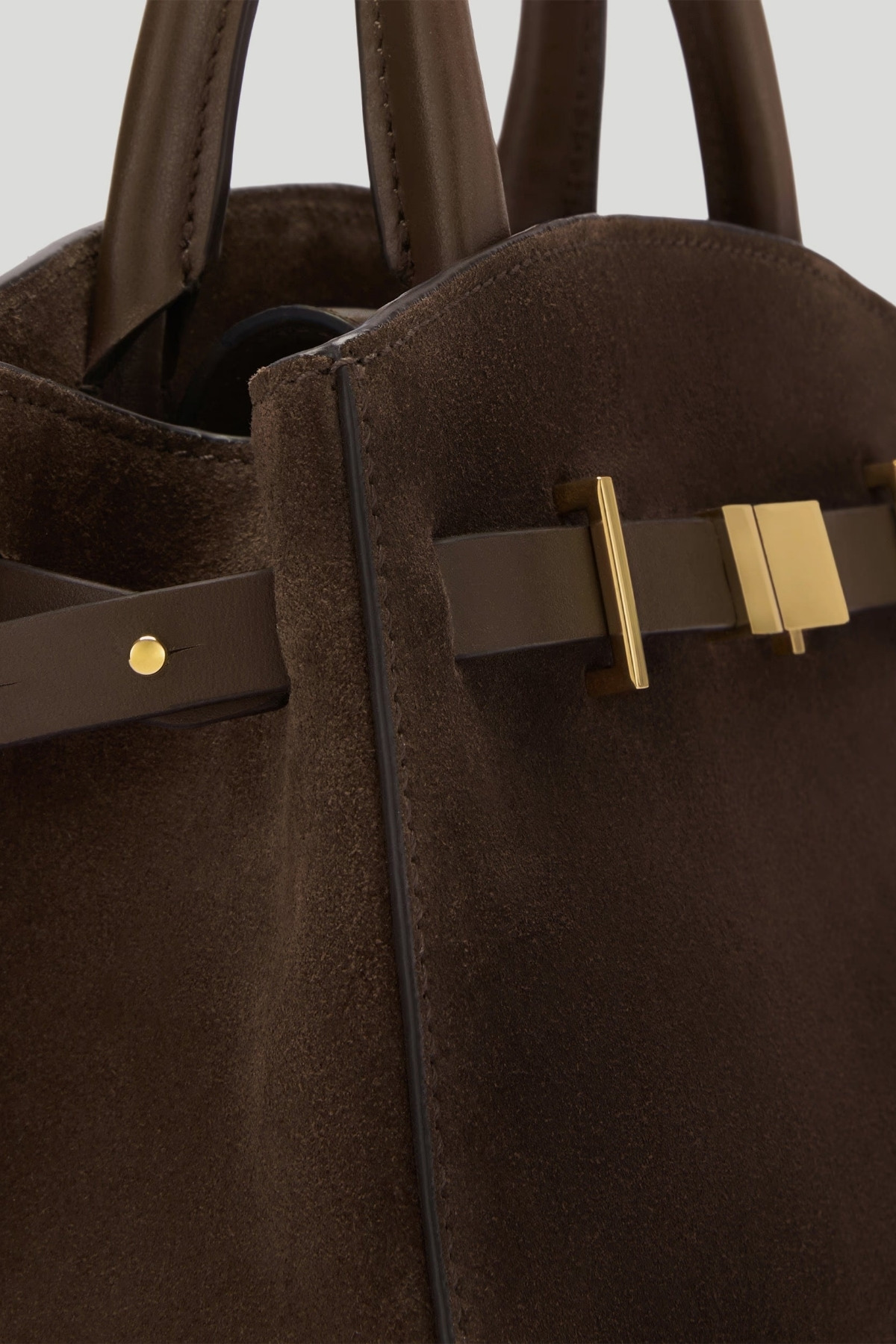 Close up detailing of the DeMellier Small Hudson bag in dark brown suede, with gold hardware.