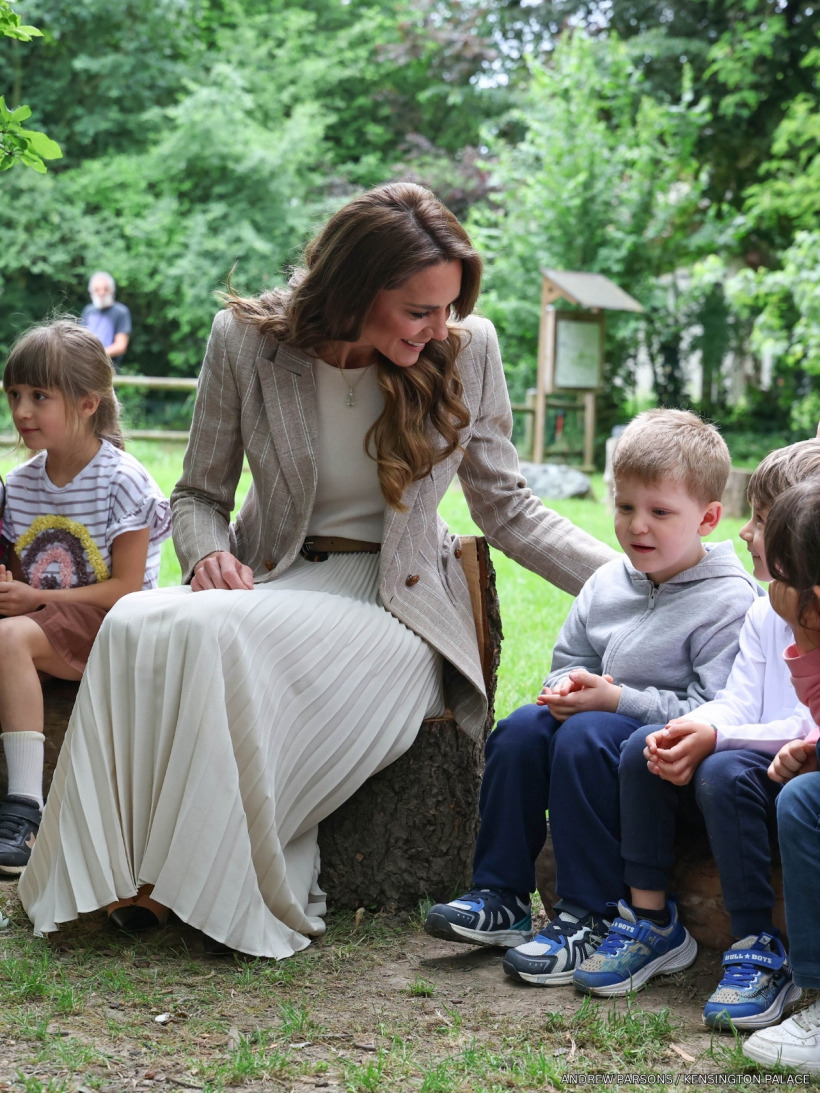 The Princess of Wales sitting outdoors with children during the morning assembly at Salvador Allende pre-school.
