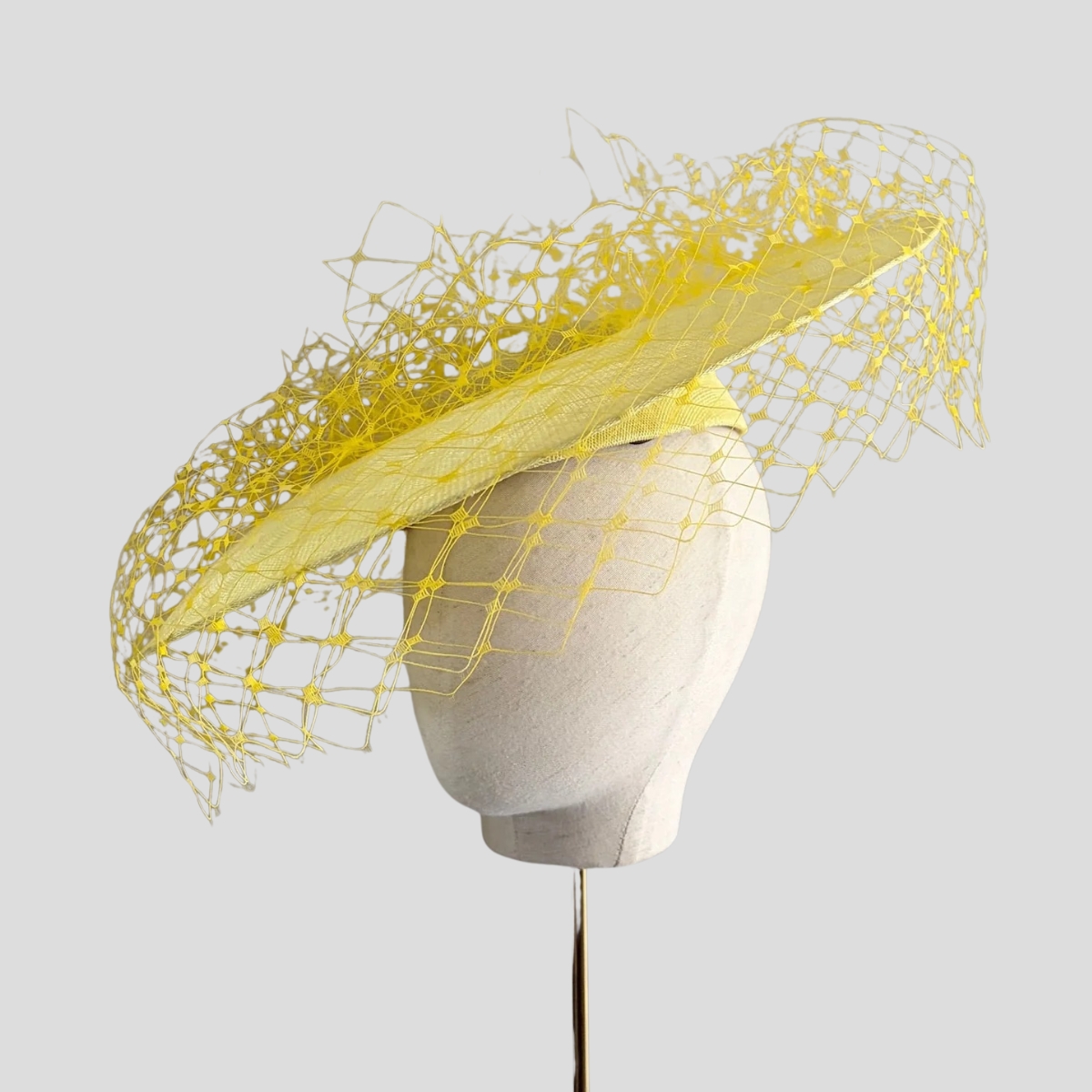 The Jane Taylor 'Epona' hat in yellow, with a wide downturned brim and veiling
