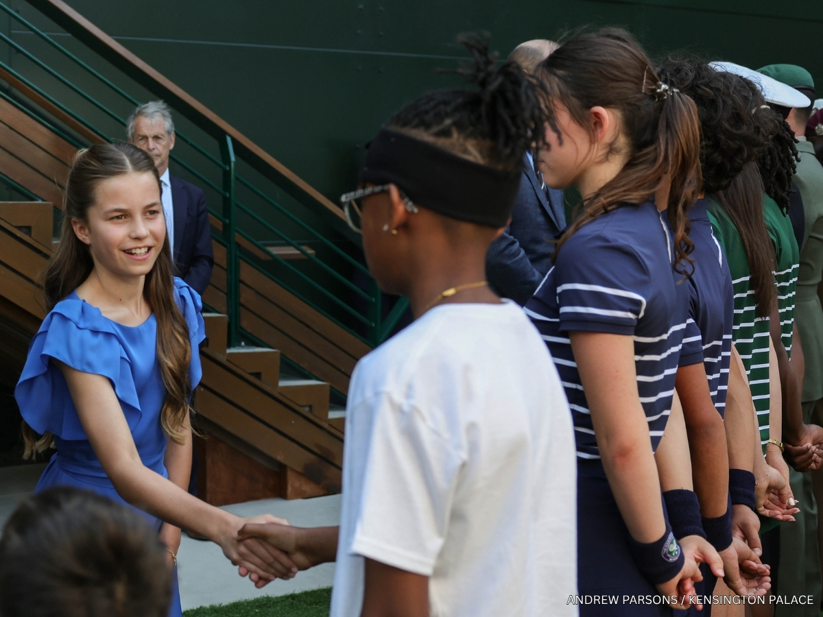 Princess Charlotte in a cobalt blue dress with ruffled sleeves meeting staff at Wimbledon